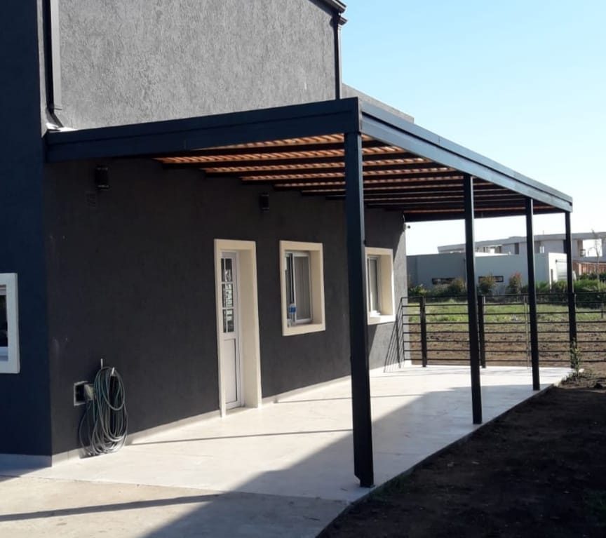 Galería metálica con techo de madera al frente de una vivienda